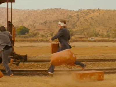 3 men in outback carrying suitcases and running to jump on old fashioned train