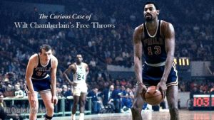 wilt Chamberlin holding basketball about to shoot other players and packed stadium in background